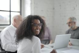 black woman in glasses and white shirt smiling